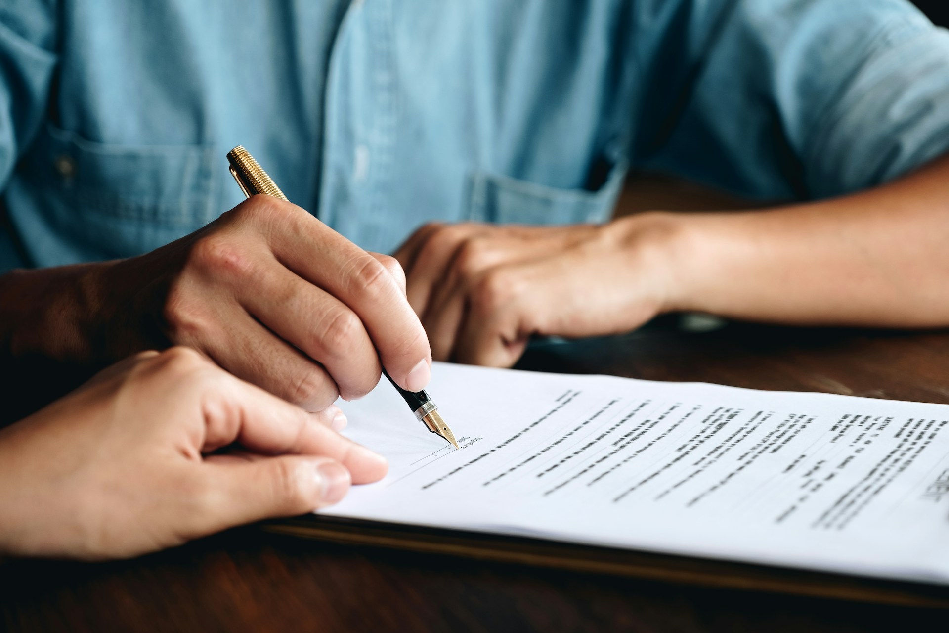 Business litigation contract being signed by a man and woman at a table, highlighting their formal agreement.